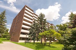 Guelph apartment for rent - A tall brown building with a grassy area in front of it.