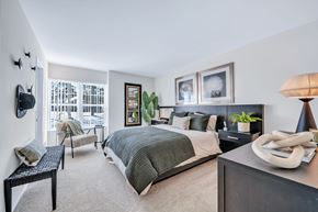 Farmington Hills apartment for rent - A bedroom with a large bed and a window overlooking a balcony.