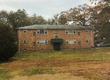 Bloomfield apartment for rent - A brick building with a green roof and a car parked in front.