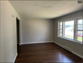 St. Louis house for rent - A room with wooden floors and a window showing a view of a parking lot and a red car.