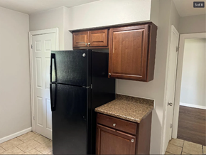 St. Louis house for rent - A black fridge in a kitchen with brown cabinets.