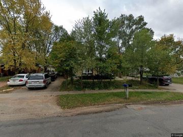 Stevens Point apartment for rent - A street view with cars parked on the side and trees in the background.