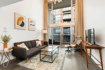 Seattle apartment for rent - A living room with a black couch, a coffee table, and a flat screen TV.