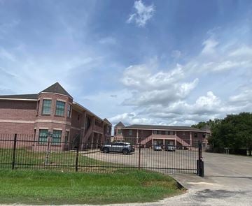 El Campo apartment for rent - A large brick building with a black fence in front.