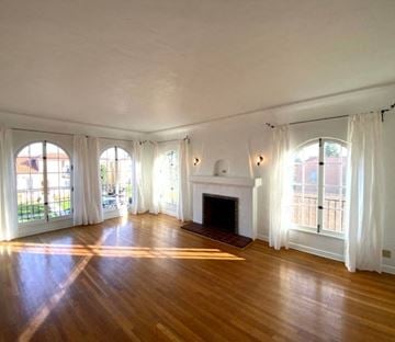 Los Angeles house for rent - A large, empty room with wooden floors and a fireplace.