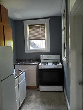 Baltimore apartment for rent - A kitchen with a white fridge, white oven, and a window with blinds.