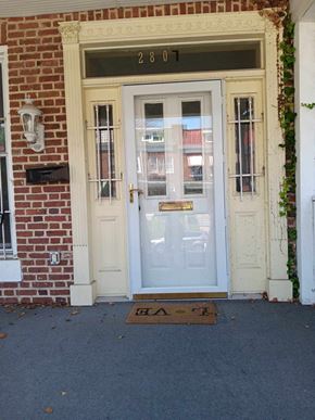 Baltimore apartment for rent - A white door with a glass window and a mailbox on a brick wall.