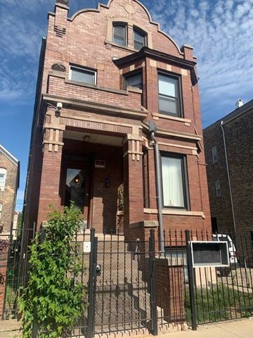 Chicago apartment for rent - A red brick building with a black fence in front.