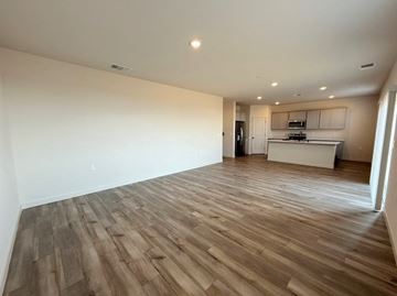 Merced house for rent - A room with wooden flooring and a kitchen in the background.