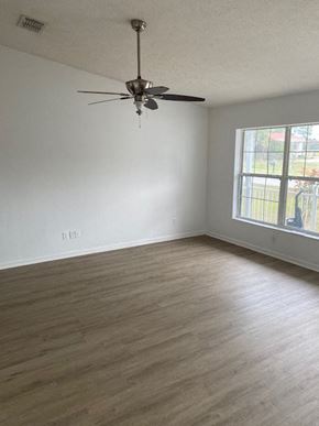 Homosassa house for rent - A room with a ceiling fan and light fixture.