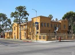 Los Angeles apartment for rent - A yellow building is situated on a street corner with a traffic light in front of it.