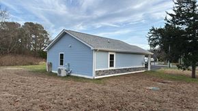 Pocomoke City house for rent - A blue house with a white door and a window is surrounded by a grassy field.