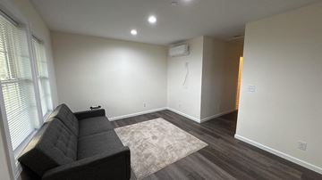 Pocomoke City house for rent - A living room with a black couch and a rug.