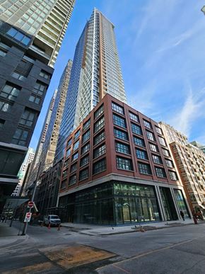 Toronto apartment for rent - A tall building with a red brick facade stands in front of two taller buildings.