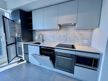 Toronto apartment for rent - A kitchen with white cabinets and black appliances.