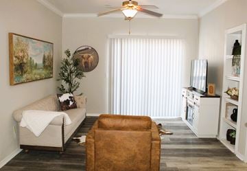 Oklahoma City apartment for rent - A living room with a brown leather chair and a painting of a landscape on the wall.