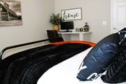 Oklahoma City apartment for rent - A black and white bedroom with a black bed and a white shelf with a plant on it.