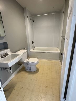 Lima house for rent - A white toilet is in a bathroom with a white sink and bathtub.