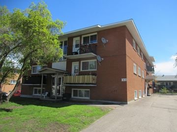 Pembroke apartment for rent - A red brick apartment building with a balcony and a tree in front.