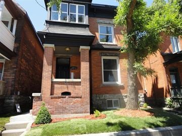 Ottawa apartment for rent - A red brick house with a tree in front.