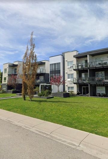 Calgary house for rent - Apartment buildings with a tree in front of them.
