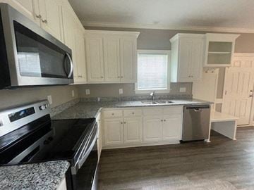 Wilson apartment for rent - A kitchen with white cabinets and a black microwave.