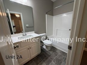 Wilson apartment for rent - A bathroom with a toilet, sink, and mirror.