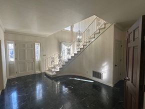 Knoxville, Tn house for rent - A spacious foyer with a marble floor and a staircase with a metal railing.