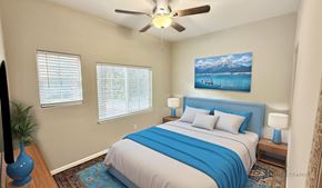 Golden apartment for rent - A bedroom with a bed, a ceiling fan, and a painting of a mountain scene on the wall.