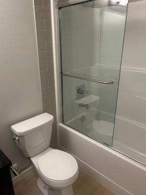 Calgary apartment for rent - A white toilet sits next to a glass shower door.