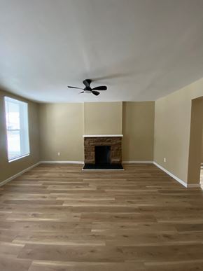 Louisville house for rent - A room with a fireplace and a ceiling fan.