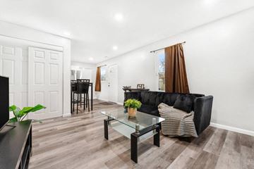 Gary house for rent - A black couch with a striped pillow sits in a living room with a glass coffee table.