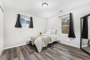Gary house for rent - A bedroom with a bed, wooden floor, and a window with curtains.