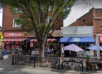 Charlottesville apartment for rent - A street view of a restaurant with people sitting at tables under umbrellas.