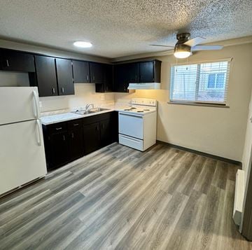 Fountain apartment for rent - A kitchen with white appliances and black cabinets.