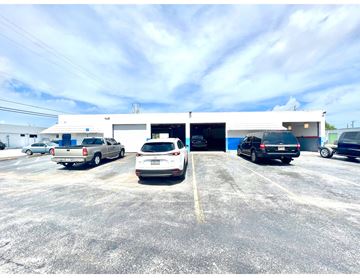 Pompano Beach apartment for rent - A parking lot with cars and a building in the background.