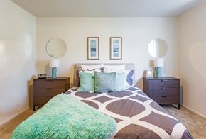 Westland apartment for rent - A bedroom with a bed, two nightstands, and two round mirrors on the wall.