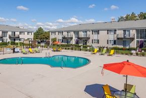 Westland apartment for rent - A swimming pool surrounded by chairs and umbrellas in front of apartment buildings.