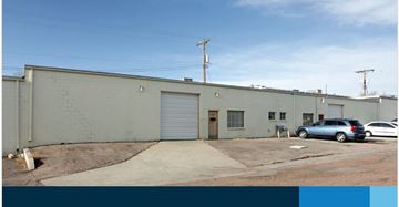 Colorado Springs apartment for rent - A grey building with a closed white door and a grey car parked in front.
