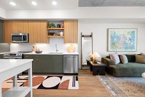 Raleigh apartment for rent - A modern kitchen with a greenish tone to the cabinets and a white dining table.