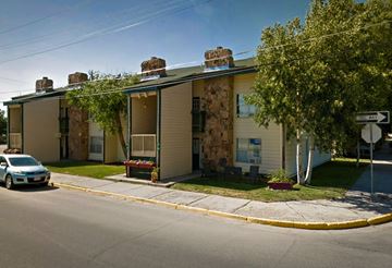 Craig apartment for rent - A red car is stuck in a snow bank in front of a building.