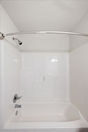 Sterling Heights apartment for rent - A white bathroom with a white tub and a silver shower rod.