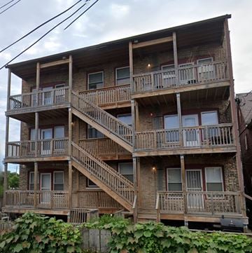 Chicago apartment for rent - A large wooden apartment building with multiple balconies and staircases.