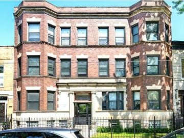 Chicago apartment for rent - A large red brick building with a black iron fence in front.