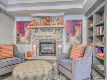 Germantown apartment for rent - A living room with a grey couch, a grey ottoman, and a fireplace with a painting above it.