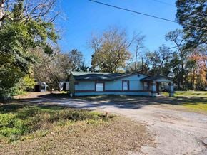 Jacksonville house for rent - A house with a green roof is surrounded by trees and grass.