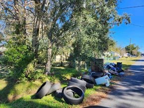 Jacksonville house for rent - A pile of old tires are on the grass by the road.