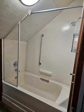 Everett house for rent - A white bathtub with a glass door and a shower head.