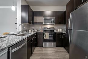 Houston apartment for rent - A modern kitchen with dark wood cabinets and stainless steel appliances.