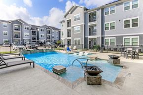 Houston apartment for rent - A swimming pool with a slide and a hot tub in front of apartment buildings.